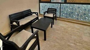 Un balcon aménagé avec un canapé, des chaises et une table, offrant une vue sur les bâtiments et un ciel dégagé.