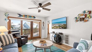 Ein Wohnzimmer mit Sofa, Sessel, Couchtisch und Deckenventilator.
