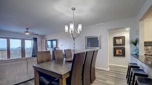 A dining area with a large table, chairs, a chandelier, and a television in the background.
