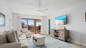 Ein Wohnzimmer mit einem beigefarbenen Sofa, einem Couchtisch, einem Fernseher und einem Bücherregal.