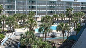 Ein mehrstöckiges Hotel mit Balkonen, einem Pool und Palmen.