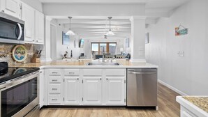 Una cocina moderna con gabinetes blancos, lavavajillas de acero inoxidable y encimera de granito.