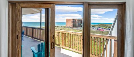 A balcony with a view of the ocean and a distant building.