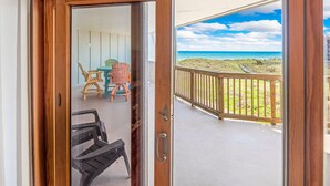 A balcony with a view of the beach and a wooden railing.