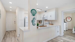 A modern kitchen with white cabinetry, a central island, and decorative wall art.