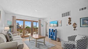 A spacious living room with a sofa, armchair, and a coffee table. There is a large window with a view of the outside. - La Mirage Condo 103 Beachfront Condo Resort with Private BoardWalk Access (Port Aransas)