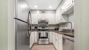A modern kitchen with white cabinets, stainless steel appliances, and a granite countertop.