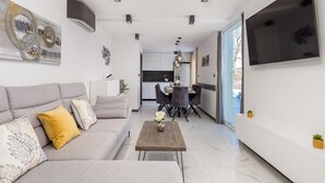 Uma sala de estar moderna com um sofá, mesa de centro e uma TV fixada na parede.