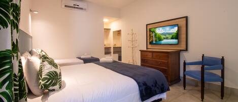 A hotel room with a bed, a television, a chair, a dresser, and a mirror.