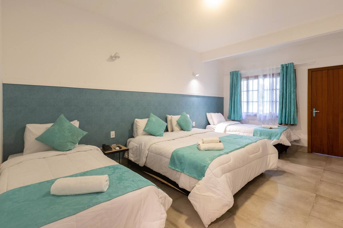 Une chambre d’hôtel avec deux lits, une table de chevet, un téléphone et une porte.