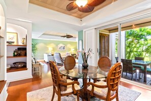 Un comedor con mesa de vidrio, sillas de madera y vistas al exterior.