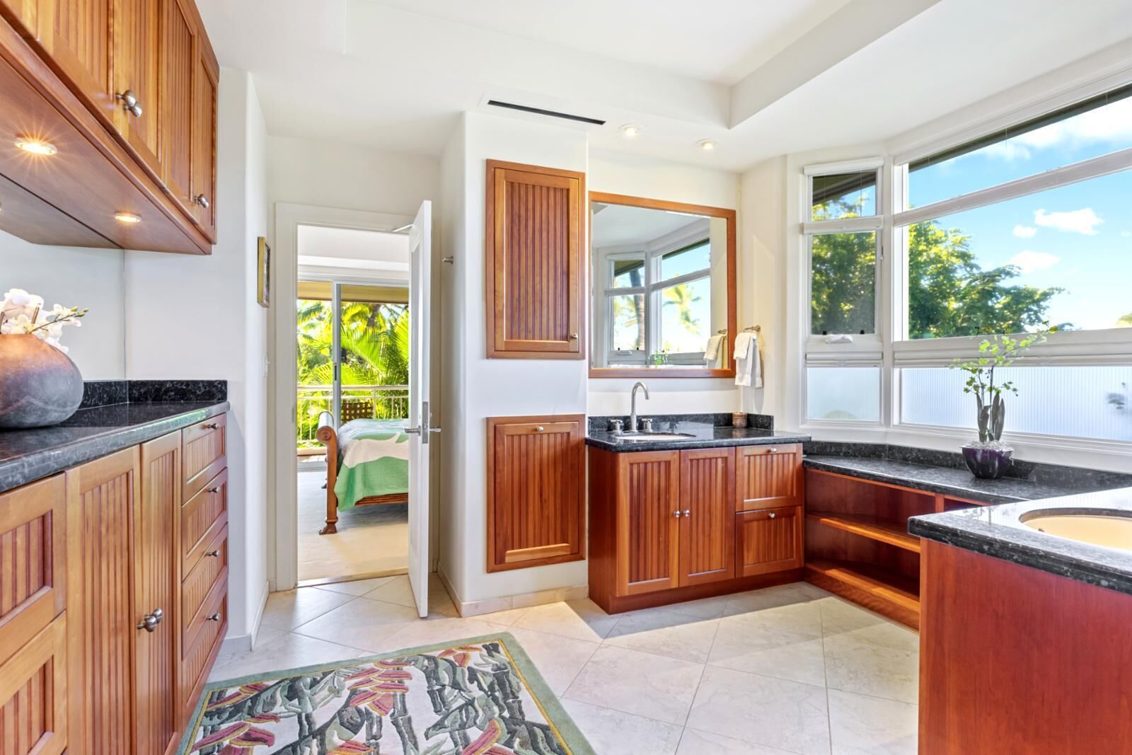 A modern kitchen with wooden cabinets, a large window, and a view of a balcony.