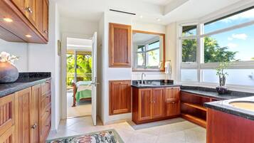 A modern kitchen with wooden cabinets, a large window, and a view of a balcony.