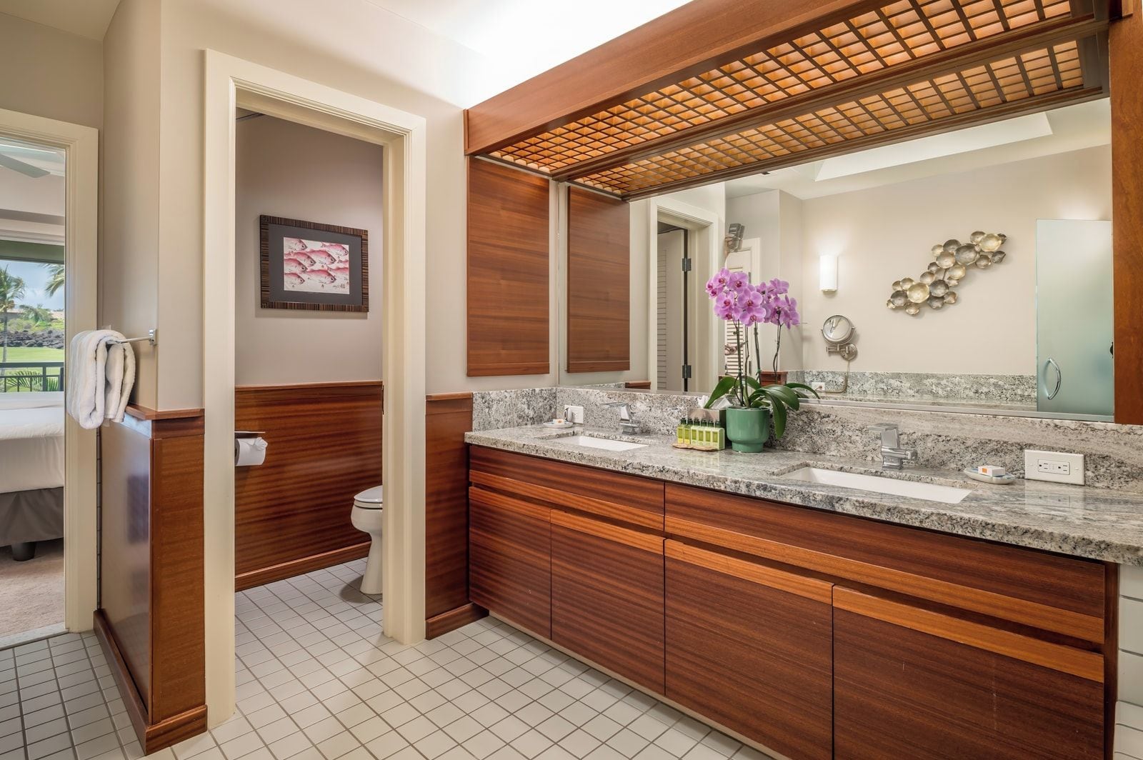 A modern bathroom with a wooden vanity, a large mirror, and a granite countertop.