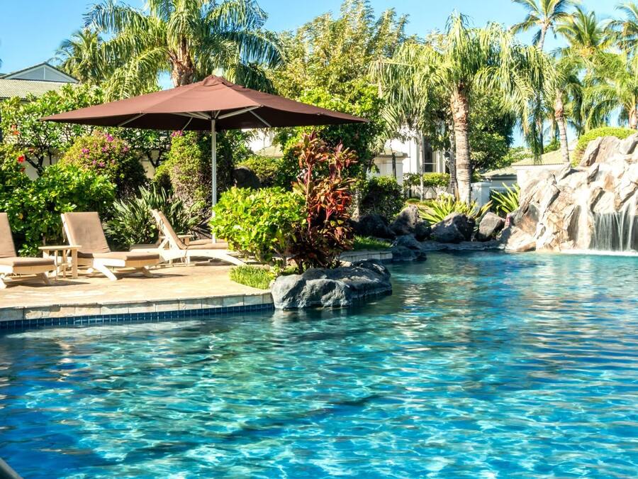 A swimming pool with lounge chairs and a waterfall feature.