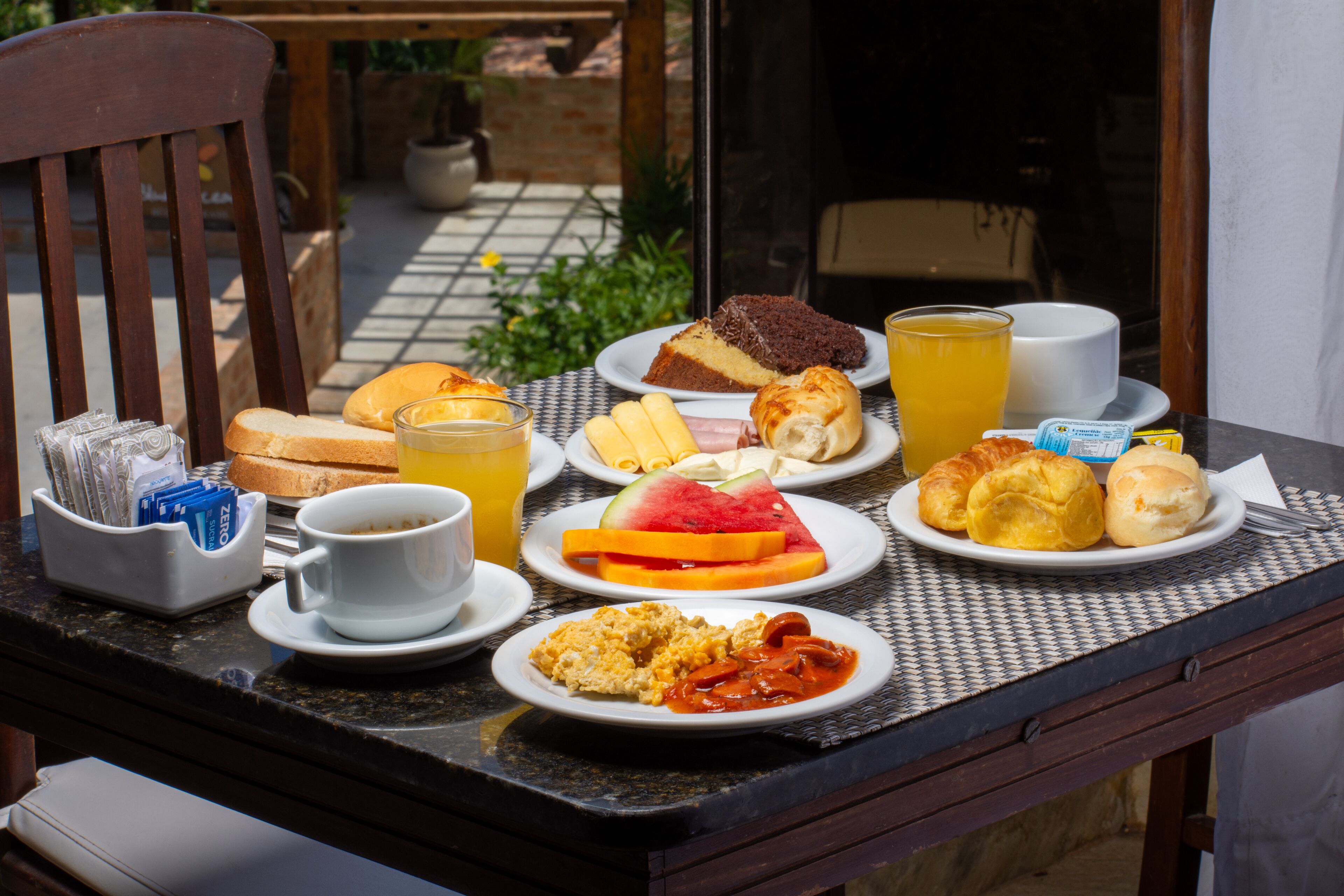 A breakfast table with various food items and a cup of orange juice.
