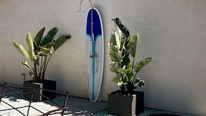 A wall-mounted shower with a blue and white design, two potted plants, and a metal chair. - Coastal Compound - Two Fully Equipped 3BRs - 31+ Day Stay (Oceanside)