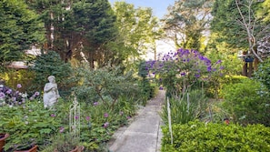 Stroll through a serene garden, surrounded by vibrant blooms and a classical statue.