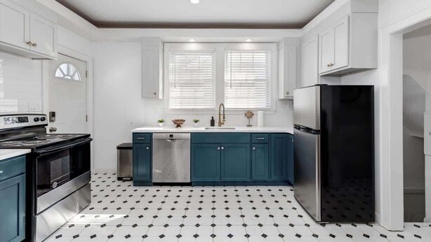 A kitchen with white cabinets, a black refrigerator, and a patterned floor. - Sleeps 14! 10 Mins to Downtown + Driveway Parking (Detroit)