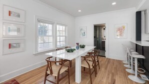 A modern kitchen with white cabinetry, a central island, and bar stools. - Sleeps 14! 10 Mins to Downtown + Driveway Parking (Detroit)