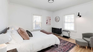 A bedroom with a bed, bedside tables, a desk, a chair, and a window. - Sleeps 14! 10 Mins to Downtown + Driveway Parking (Detroit)
