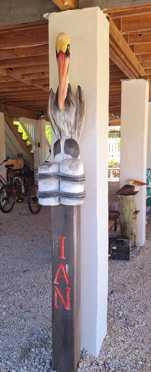 A wooden post with a bird sculpture and the name "IAN" painted on it.
