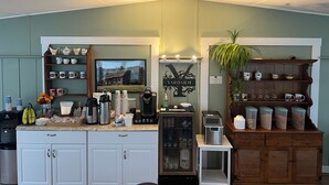 Eine Küche mit weißen Schränken, einer Kaffeemaschine und einem Fernseher, der ein Haus zeigt.