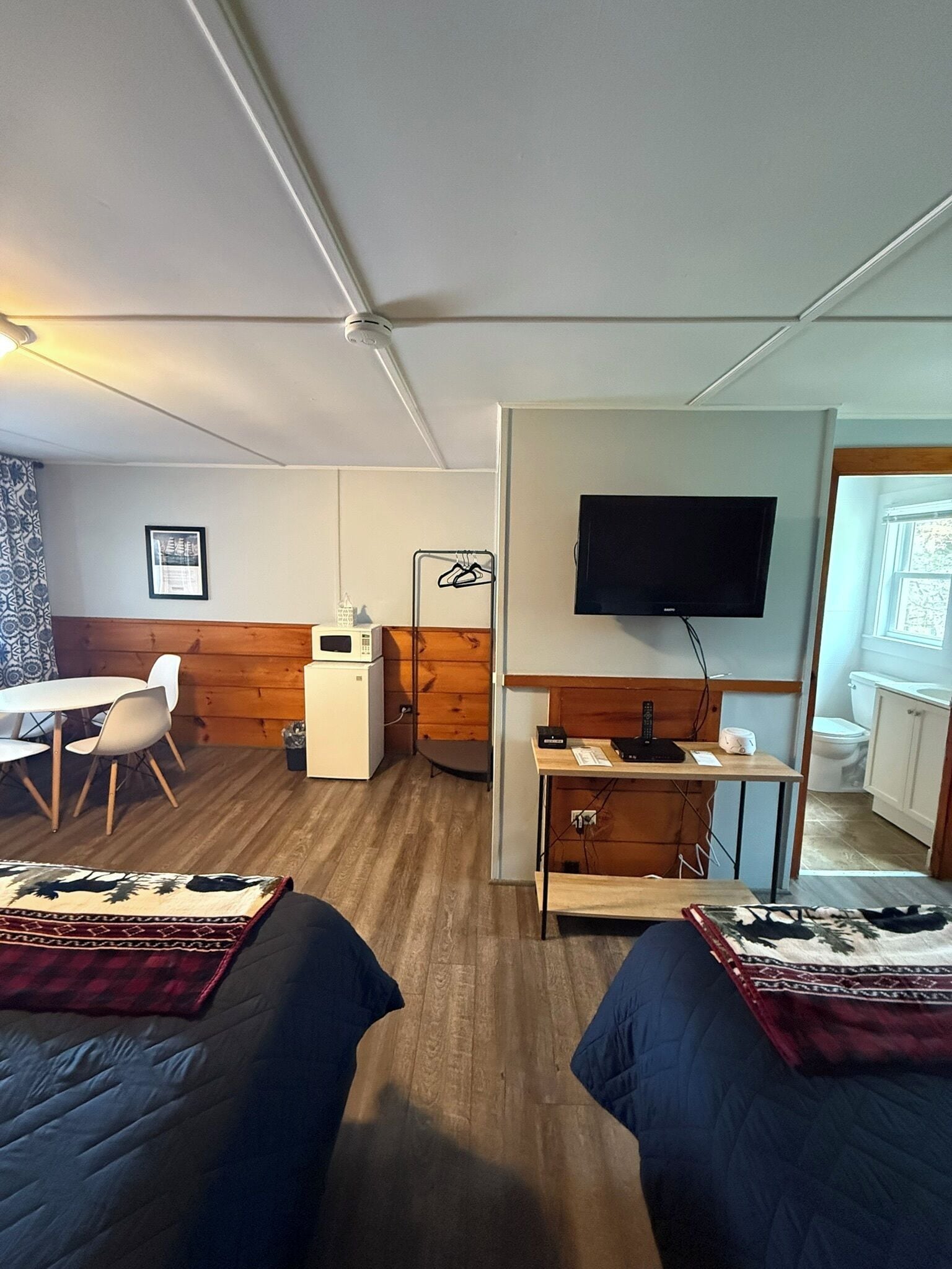Habitació amb dos llits, escriptori, televisió i petita cuina.