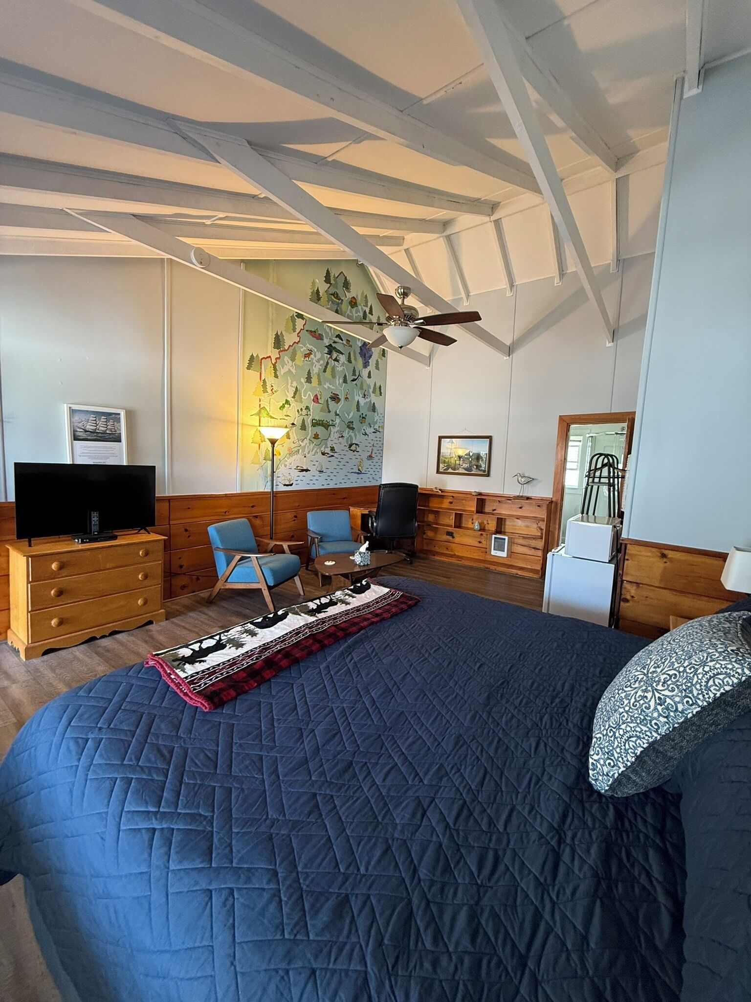Une chambre dotée d’un grand lit, d’un ventilateur de plafond, d’une télévision et d’une fresque murale.
