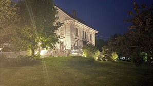 Ein großes, historisches Haus mit gepflegtem Rasen und einem weißen Zaun.