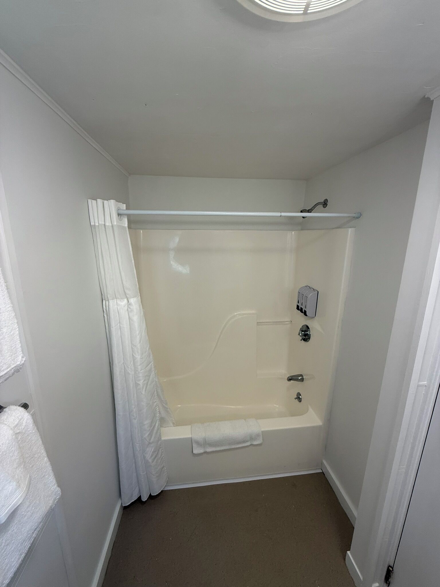 A small, white bathroom with a bathtub, a shower curtain, and a towel rack.