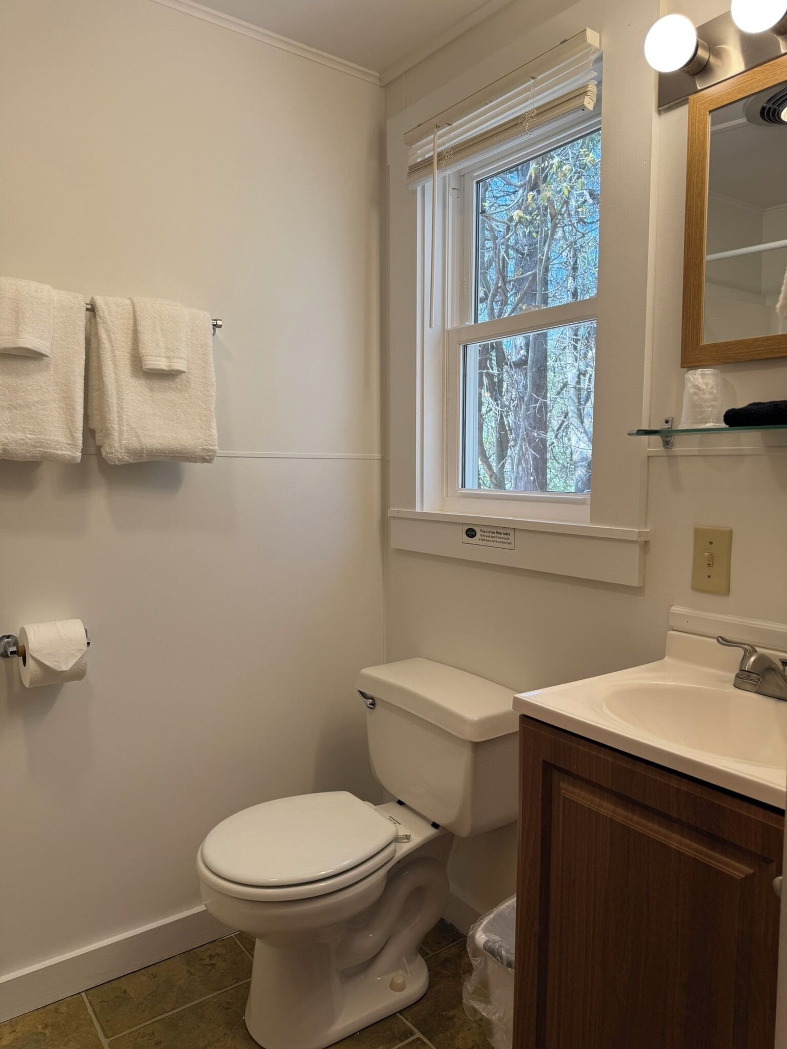 Une salle de bain avec des toilettes, un lavabo et une fenêtre.
