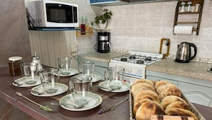 A kitchen with a microwave, stove, and various kitchen items. - El Nogal, Acogedora Cabaña con Jardín y Cochera (Vistalba Luján de Cuyo)