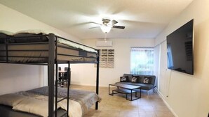 A bunk bed room with a ceiling fan, a sofa, and a TV. - SALE! Peaceful, Clean, 4x Queen Bed, Spacious! (Hemet)