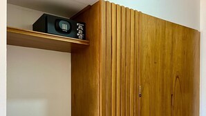 A wooden wardrobe with a black countertop and a shelf above it. - NEO BUSINESS HOTEL (Culiacán)