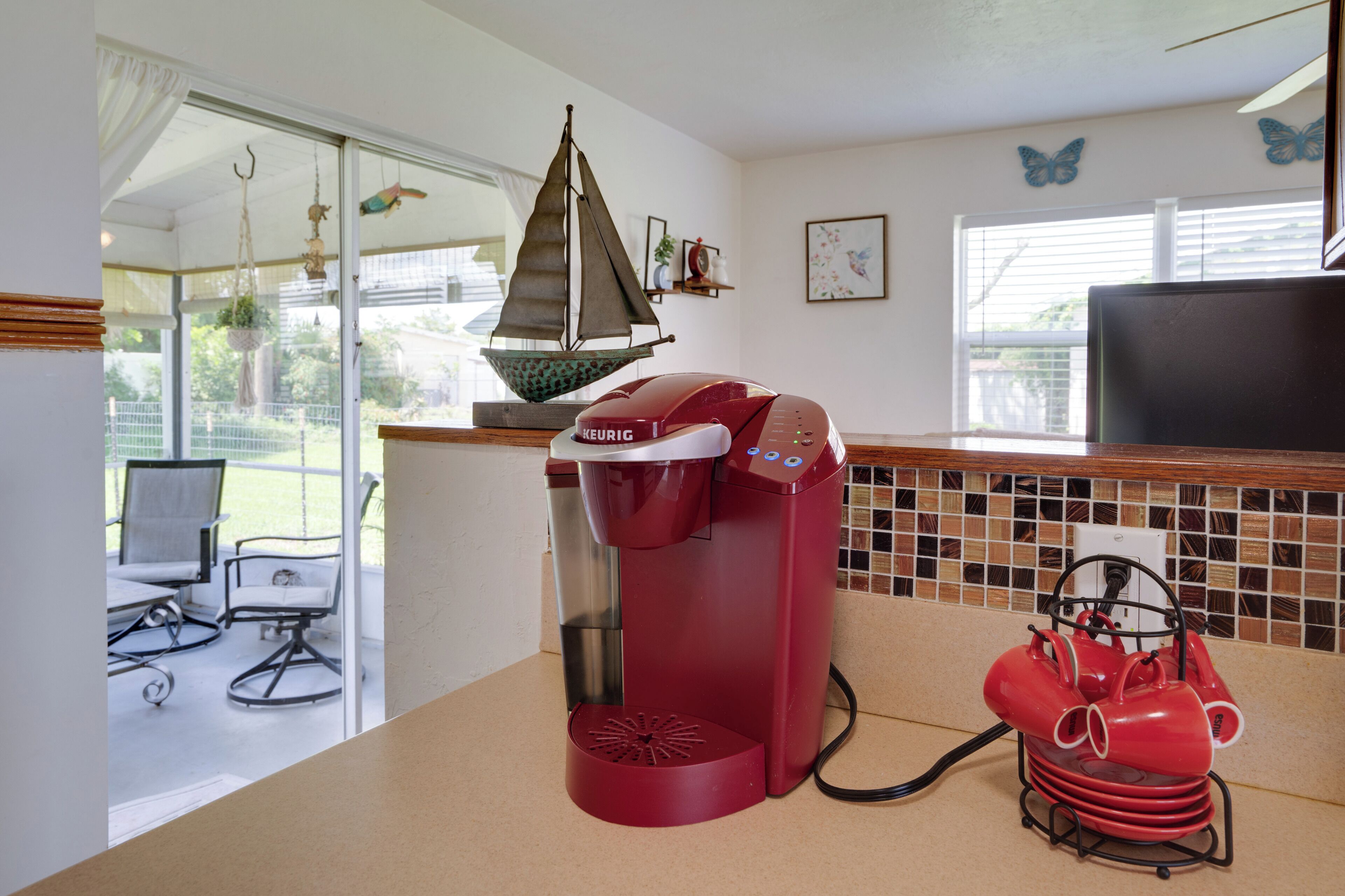 Una cucina con una macchina da caffè, una decorazione a forma di barca a vela e vista sull'esterno.