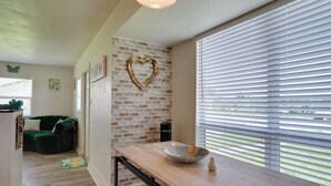 A modern kitchen with a wooden table, a heart-shaped decoration on the brick wall, and a window with blinds. - Charming & Cozy: Close to Beach & Shops ~ Parking! (Port Charlotte)