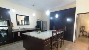 A modern kitchen with a central island, dark cabinetry, a microwave, and a refrigerator. - One bedroom apartment, quiet & relaxing atmosphere (Bucerias)