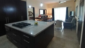 A modern kitchen with dark cabinetry, a central island, and pendant lighting. - One bedroom apartment, quiet & relaxing atmosphere (Bucerias)