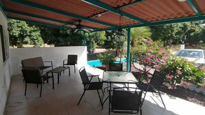 A covered patio area with a pool, outdoor seating, and a car parked nearby. - One bedroom apartment, quiet & relaxing atmosphere (Bucerias)