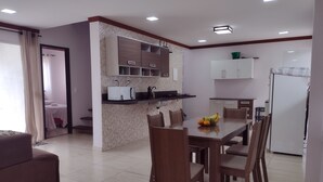 A modern kitchen with a dining area, featuring a central island, built-in cabinets, and a refrigerator.