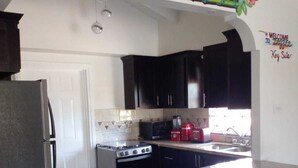 A kitchen with dark cabinets, a stainless steel refrigerator, a stove, and a sink. - PLAN YOUR GETAWAY UNDER THE SUN 
           Dazzle Key Suite (Saint Ann's Bay)