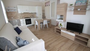 Een moderne woonkamer met een bank, televisie en een eethoek.