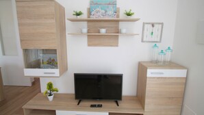 Een moderne woonkamer met een flatscreen televisie, houten kasten en decoratieve planken.