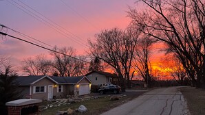 A residential street with houses, a mailbox, and a sunset.