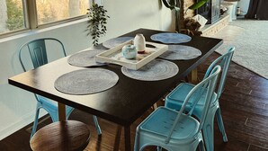 A dining area with a dark wooden table, blue chairs, and a hanging light fixture.