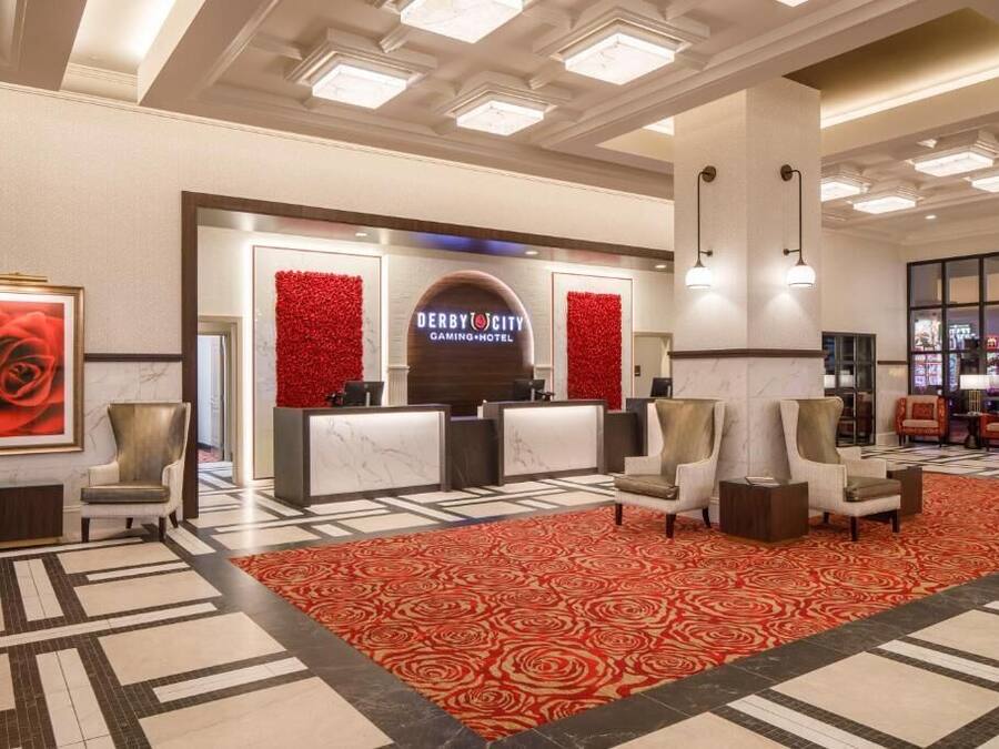 Un vestíbul d'hotel amb taulell de recepció, zona de seients i una catifa vermella.
