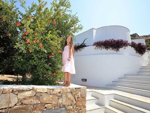 A person standing on a stone ledge with a white building and steps in the background.