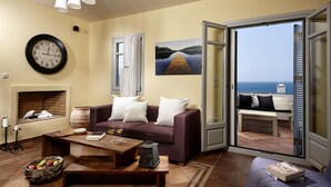 A living room with a sofa, coffee table, and a view of the sea through an open door. - Villa 'Azure' a seaside diamond in  Villa Paradise Boutique Hotel (Naxos)