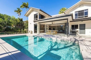 Una casa moderna con piscina, ampie finestre e una zona esterna coperta.